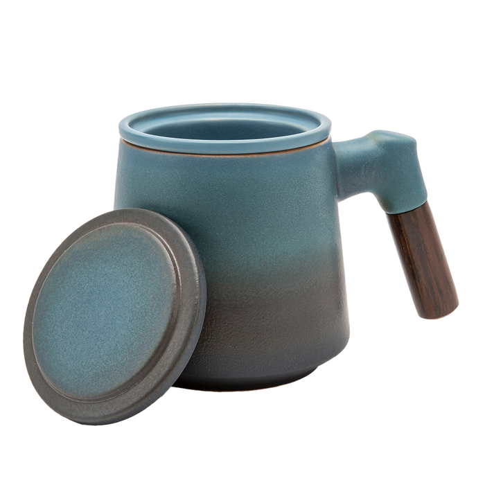 A blue ceramic tea infuser cup with a removable lid and a wooden handle.