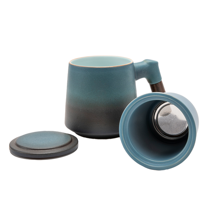 A blue ceramic tea infuser cup with a removable lid and a wooden handle.