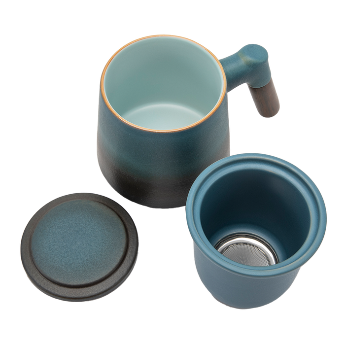 A blue ceramic tea infuser cup with a removable lid and a wooden handle.