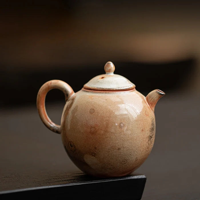 Ceramic teapot on a dark surface with a blurred background