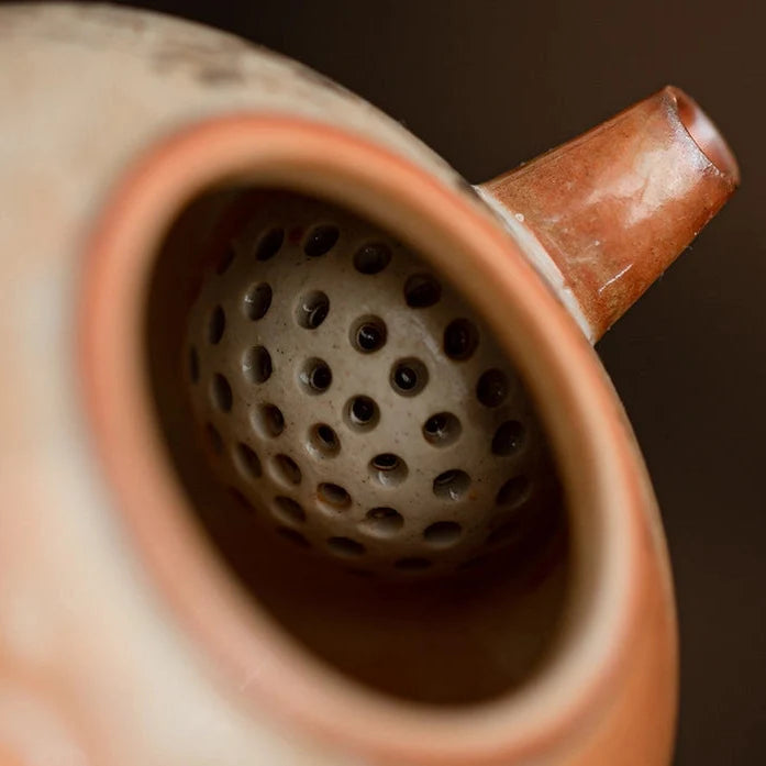 Close-up of a ceramic tea strainer with a brown background