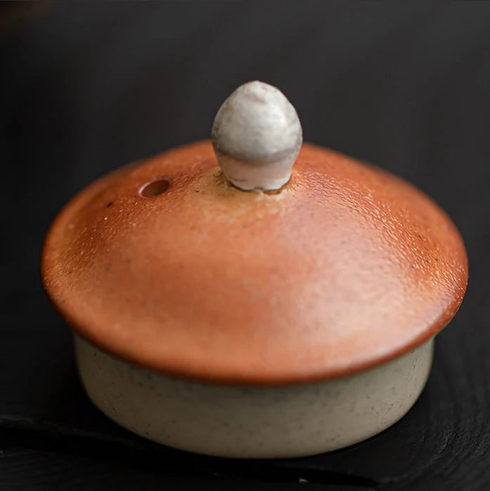 Ceramic pot with a textured brown lid on a black background