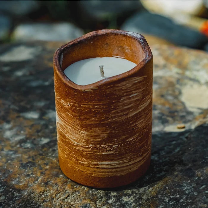Ceramic candle holder with a candle on a textured stone surface