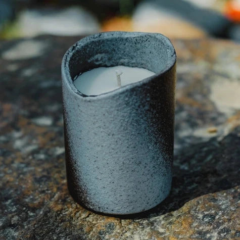 Ceramic candle holder with a candle on a textured stone surface