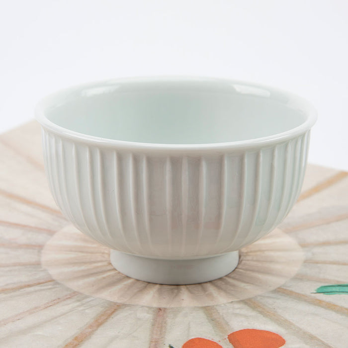 White ceramic bowl with ribbed texture on a patterned surface