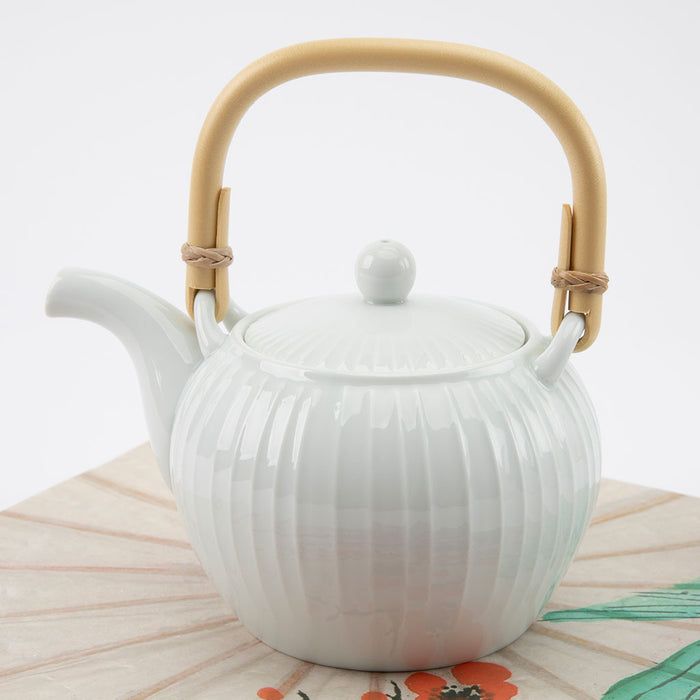 White teapot with a bamboo handle on a light background