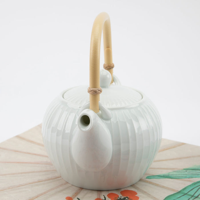 White ceramic teapot with a bamboo handle on a white background