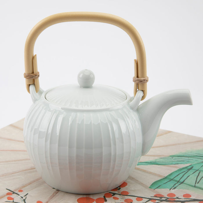 White ceramic teapot with a wooden handle on a light background