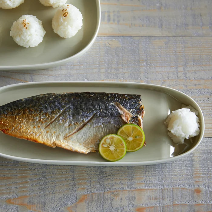 Plated fish with lemon slices and rice balls on a textured surface