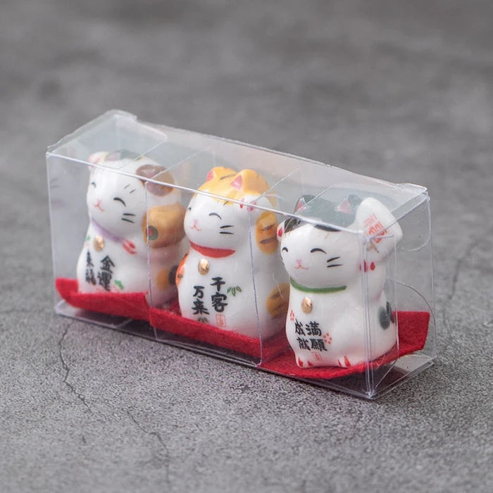 Set of four cat-shaped figurines in a clear plastic packaging on a gray surface