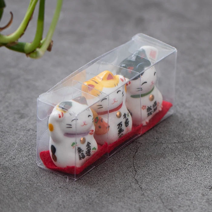 Set of four small cat figurines in a clear packaging on a gray surface