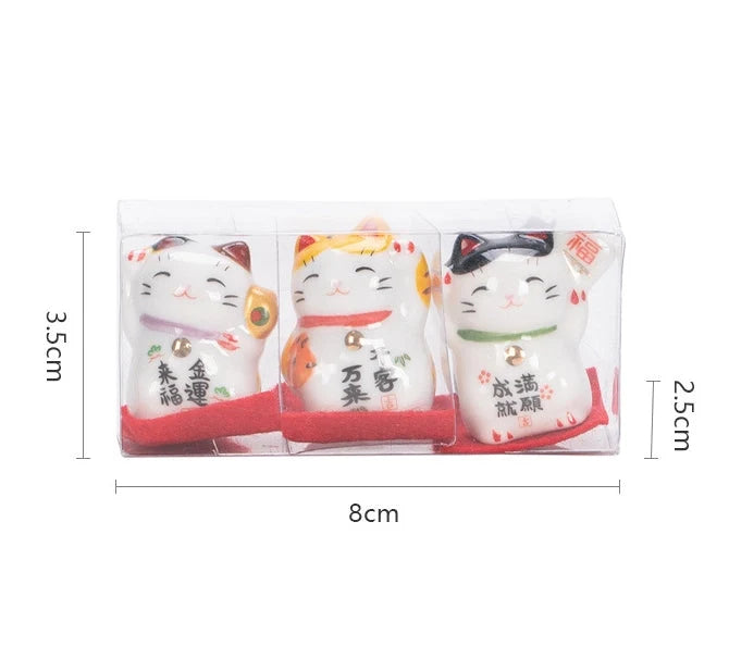 Three small ceramic cat figurines in packaging with dimensions displayed.