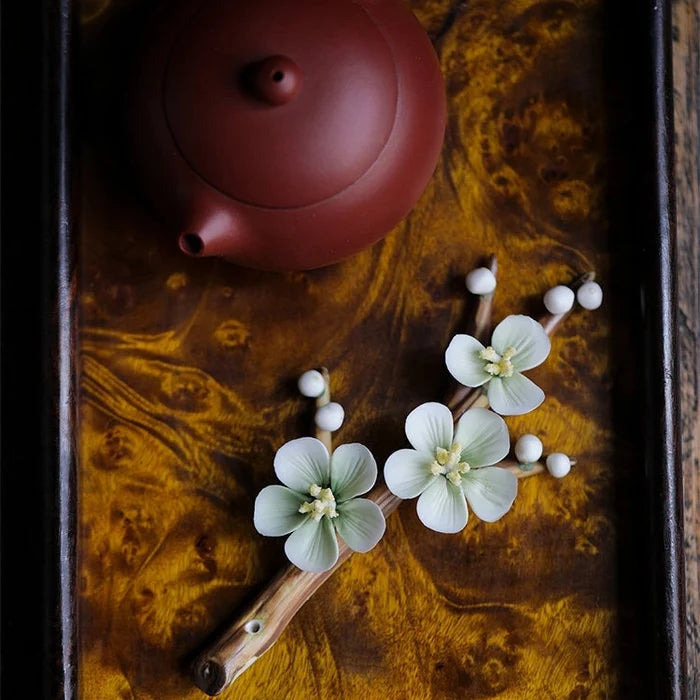 Red teapot on a dark wooden surface with decorative flowers