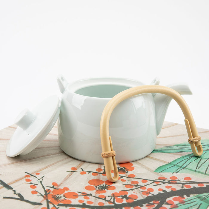 White teapot with a wooden handle on a decorative mat