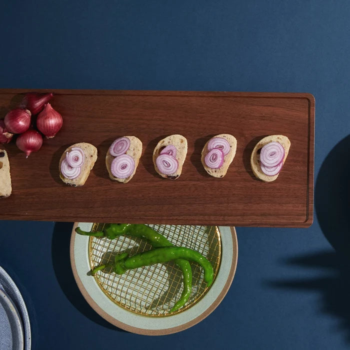 Wooden board with bread slices topped with sliced onions on a blue background