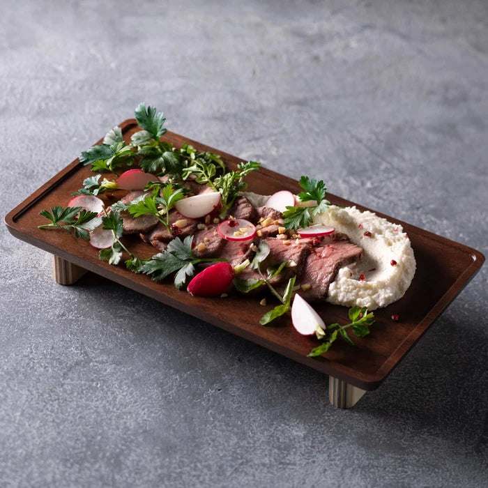 Plated dish with meat, vegetables, and a side of mashed potatoes on a gray surface