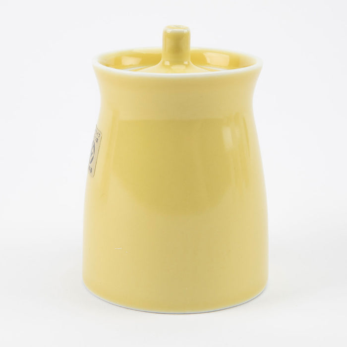 Yellow ceramic soy sauce dispenser with a handle on a white background